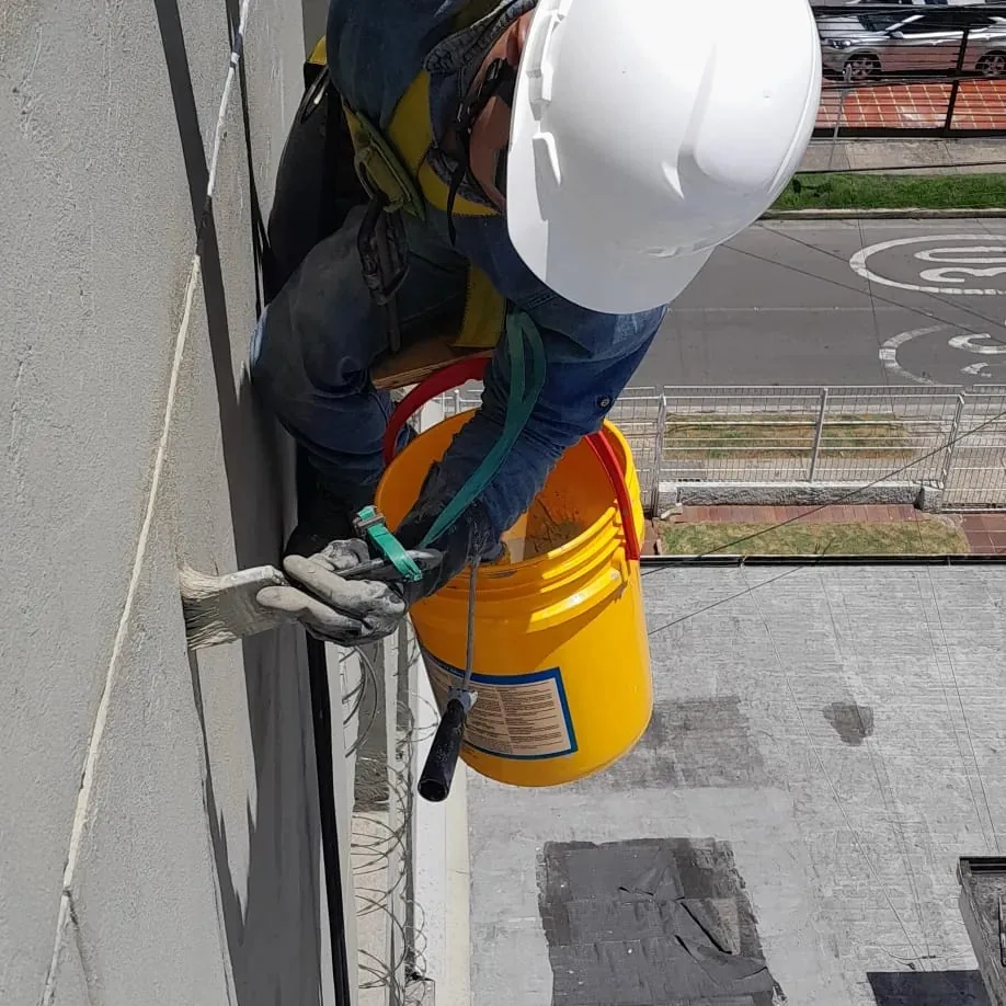Aplicación de impermeabilizante en fachada con equipo de seguridad